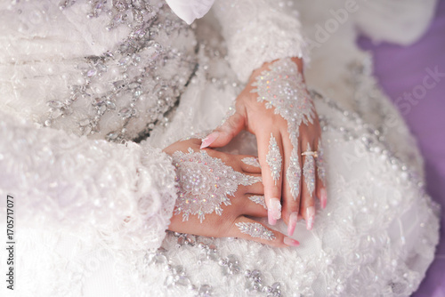 Elegant bridal hands with intricate white henna design and ring.