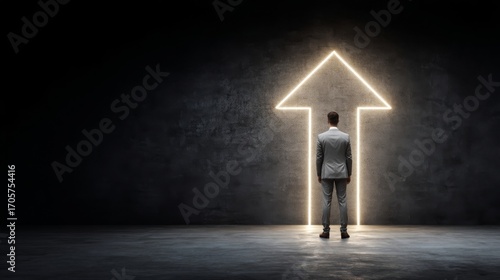 A person in formal attire stands with back turned against a dark wall, facing a neon arrow pointing upwards,
