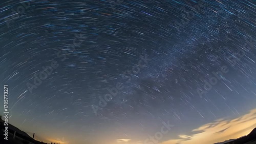 Star trails captured over a landscape during a long exposure photograph of the night sky.