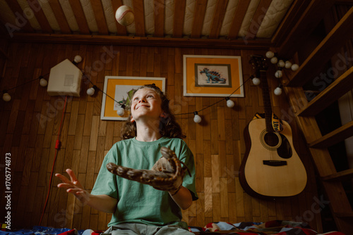 Εκτύπωση καμβά A young boy plays in his cozy room, smiling as he catches a baseball with his glove