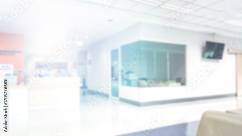 Blur abstract background of corridor in clean hospital. Blurry view of aisle in office with light floor. Defocus walkway in white light building hall with patient registration at reception desk.