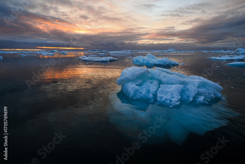 Colorful sunset reflecting on floating ice in arctic sea, Disko Bay, Greenland