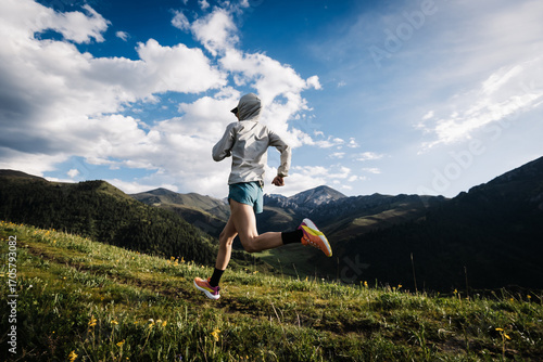 Trail runner running on the high altitude grassland mountain top trail