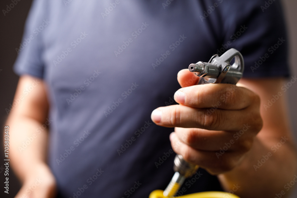 Fototapeta premium Close-up of a man's hand holding an airbrush spray gun. Ideal for DIY, painting, automotive, and industrial projects.