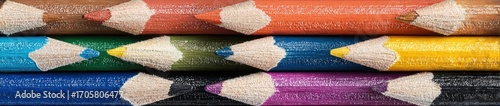 Colorful row of sharp colored pencils stacked tightly. Shades range from brown, orange, yellow, green, blue, purple and black