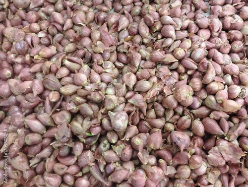 piles of shallots in supermarket display baskets, bundles of shallots sold in stores, fresh shallots in store baskets