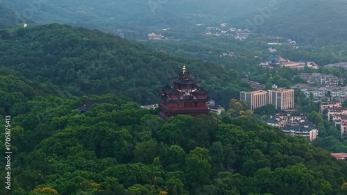 Aerial view of Chenghuang pagoda at sunset over Xihu lake in Hangzhou featuring mountains and lush green trees