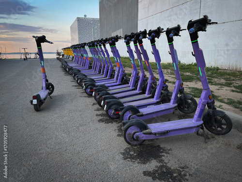 Electric scooters in the parking lot. Rental system in the city, public electric scooters on the street stand in a row, in perspective