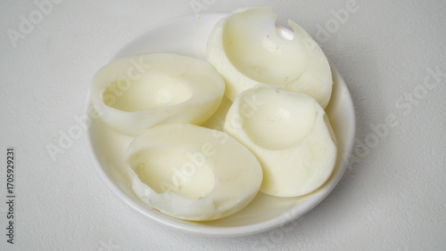 Peeled boiled eggs served on a white plate with a white background