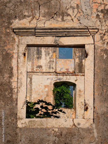 Close-up of a weathered, cracked and broken window frame and stone wall of a derelict school building in Donji Stoliv, Montenegro, damaged in the 1979 earthquake.