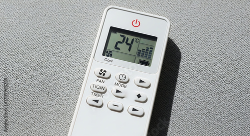 Wallpaper Mural Close-up of a white air conditioner remote control displaying a temperature of 24 degrees Celsius on a textured surface. Torontodigital.ca