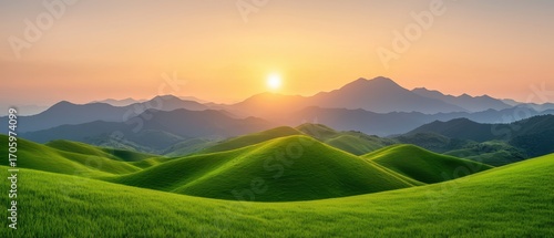 A breathtaking landscape featuring rolling green hills under a stunning sunset, with mountains in the background.