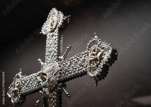 Silver crucifix in medieval Gothic style exposed with a background in shades