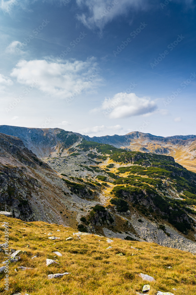 Fototapeta premium A solo traveler experiences a breathtaking autumn day in the wild Carpathian Mountains, near Lake Galcescu, in the Parang Mountains of Romania, where vibrant fall colors meet rugged peaks