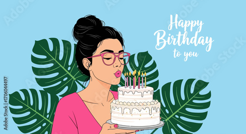 A young woman with glasses and her hair in a bun blows out candles on a two-tiered birthday cake.