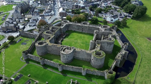 Aerial view of  the medieval ruins of Beaumaris Castle and the coastal town of Beaumaris on the Isle of Anglesey in Gwynedd off the north Wales coast. The castle dates from around 1295.