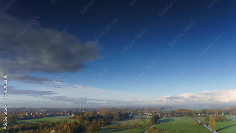 Obraz premium Breathtaking balcony view overlooking the lush green fields of Holland's countryside during a misty summer sunrise near Amsterdam, Netherlands
