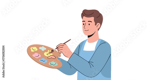 Young male artist in a blue apron smiling while mixing paints on a wooden palette with a brush.