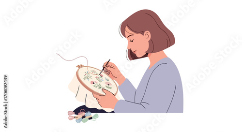Young woman with short brown hair carefully embroidering a delicate floral pattern in a wooden hoop.