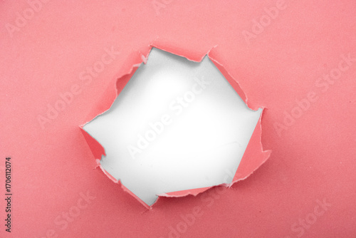 Abstract close-up of torn pink paper revealing a dark void behind
