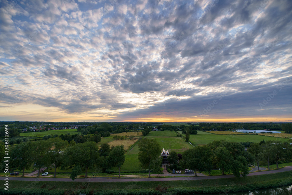 Obraz premium Breathtaking balcony view overlooking the lush green fields of Holland's countryside during a stormy summer sunset near Amsterdam, Netherlands