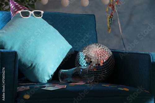 Photography Disco ball, empty glass and cushion on armchair in messy room after party