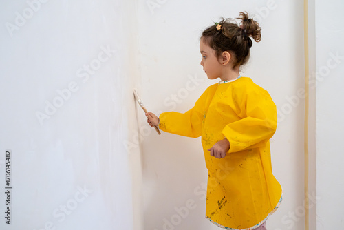 Little girl painting a room with focus and care