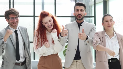 Four people are smiling and clapping their hands in a group photo