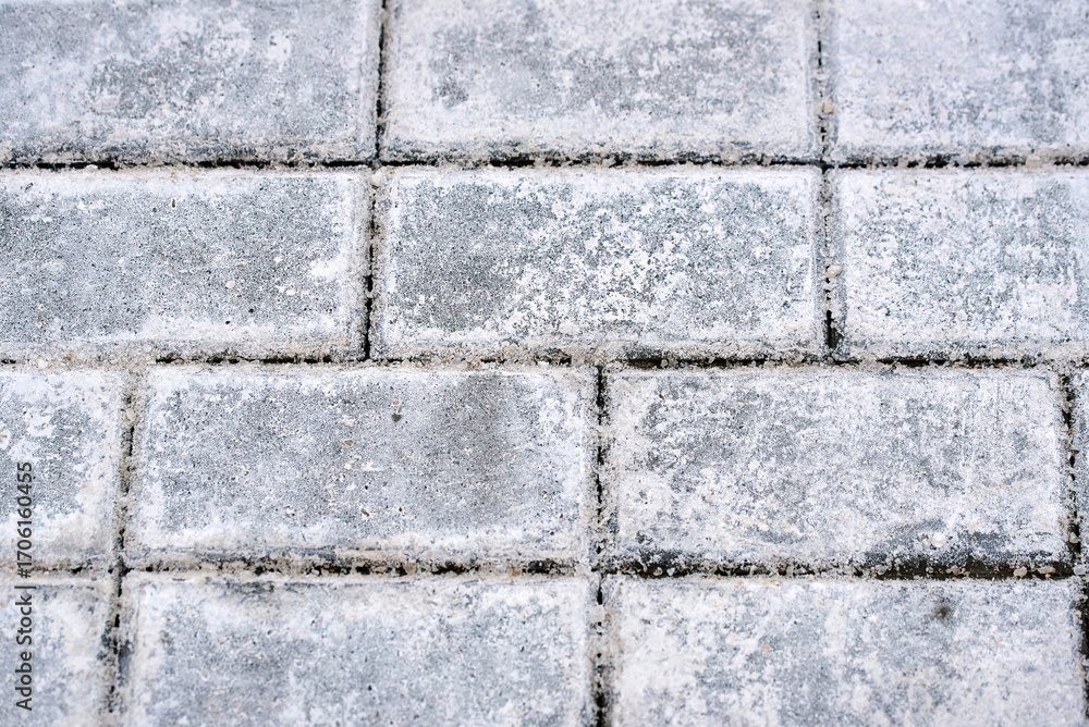 Naklejka premium Close up of paving stones with salt deposits used for ice prevention in winter, white stains texture and residue from heavy road treatment chemicals