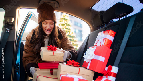 Happy woman delivering Christmas gifts to friends and family, packing Xmas presents to her car, enjoying festive mood and holiday spirit