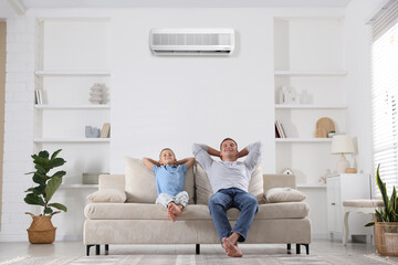 Father and his son enjoying comfortable temperature in room with air conditioner