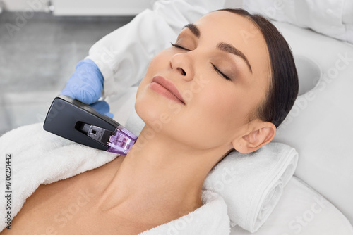 Beautiful woman doing radio frequency neck and body lifting. RF lifting procedure in beauty salon with a beautician
