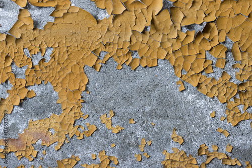 Peeling paint on the wall. Old concrete wall with cracked flaking paint. Weathered rough painted surface with patterns of cracks and peeling. Grunge texture for background and design. High resolution.