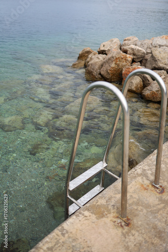A staircase with handrails leads to the sea with beautiful blue water
