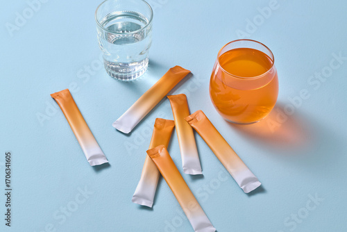 Image of a vibrant orange drink next to supplement powder sticks