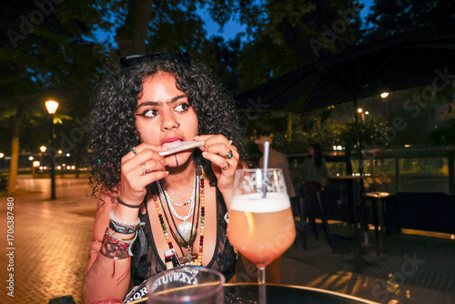 Woman Enjoying a Drink and rolling a joint Snack at night