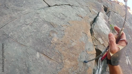 Climber's hand placing gear on rocky cliff face