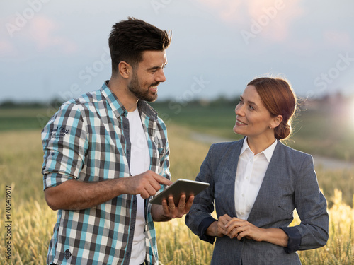 Woman and farmer looking at each other while doing business in field