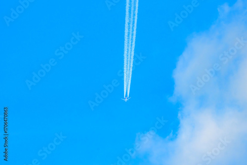 Jet airplane at high altitude leaving long contrail in clear blue sky, vapor trail phenomenon related to aviation emissions, atmosphere and climate impact concept