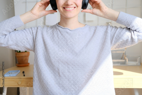Happy girl listening to music online with wireless headphones from smartphone. Woman is having fun with music with a phone and headphones. Girl uses wireless earphones