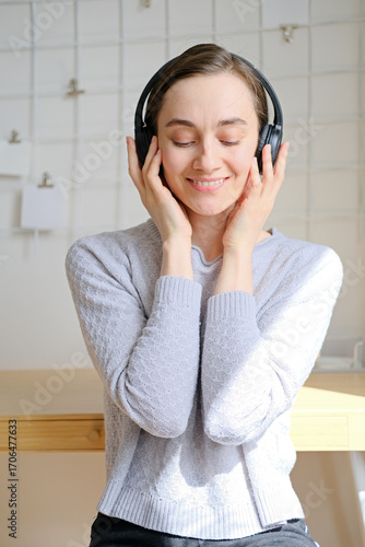 Happy girl listening to music online with wireless headphones from smartphone. Woman is having fun with music with a phone and headphones. Girl uses wireless earphones