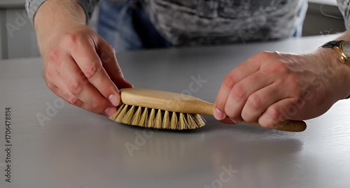 Person placing wooden brush on tabletop surface close up