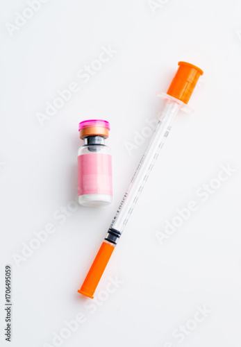 Small Pink Vial Next to Single Use Syringe on Light Background