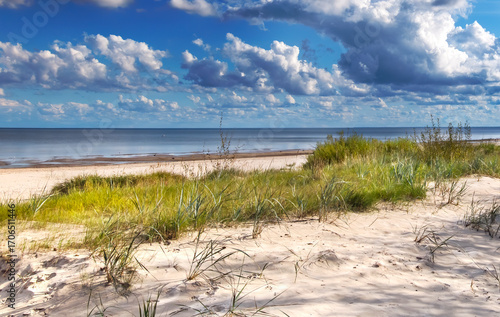 Sand dunes with grass in a shore of the Baltic Sea during summer day in Jurmala - famous tourist resort in Latvia