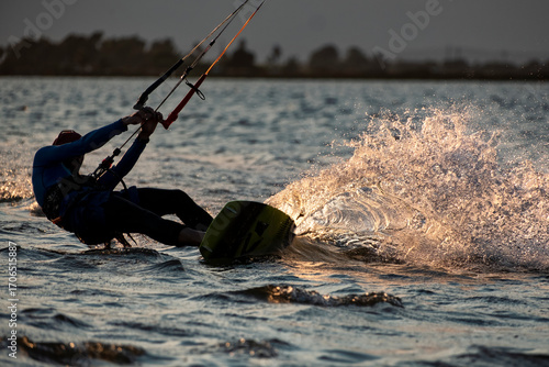 Kitesurfer carving the water at sunset backlight