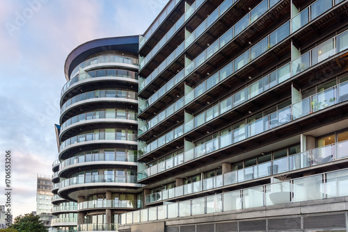Low angle view of a modern glass block of apartments in a riverside developemnt in London at dusk in winter
