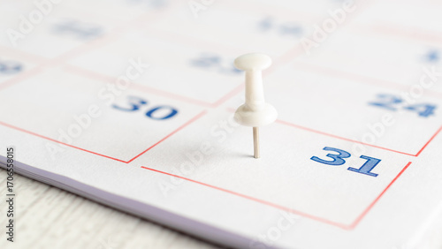 A white thumbtack on a calendar page. Business concept. 