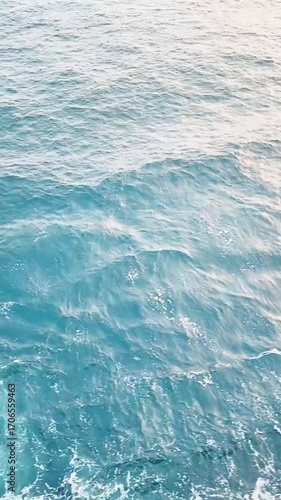 The waves of the ocean are rolling with a greenish blue color.