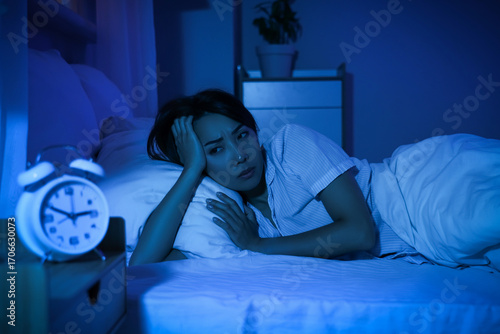 Foto Young Asian woman suffering from insomnia in bed at night