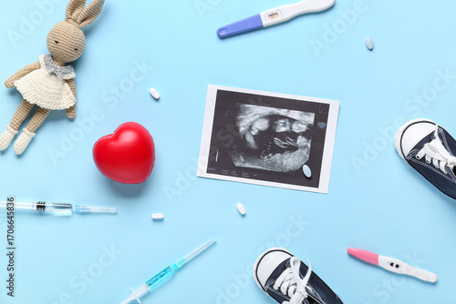 Sonogram image with heart, syringes, pregnancy tests and baby booties on blue...
